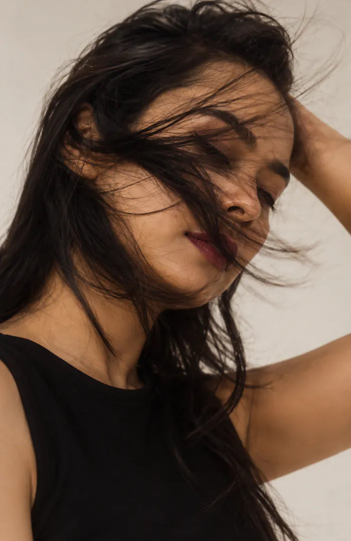 A woman with her eyes closed, running a hand through her hair