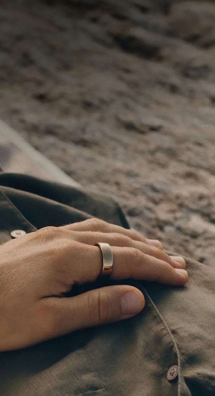 A hand resting on a blanket, wearing an Oura Ring