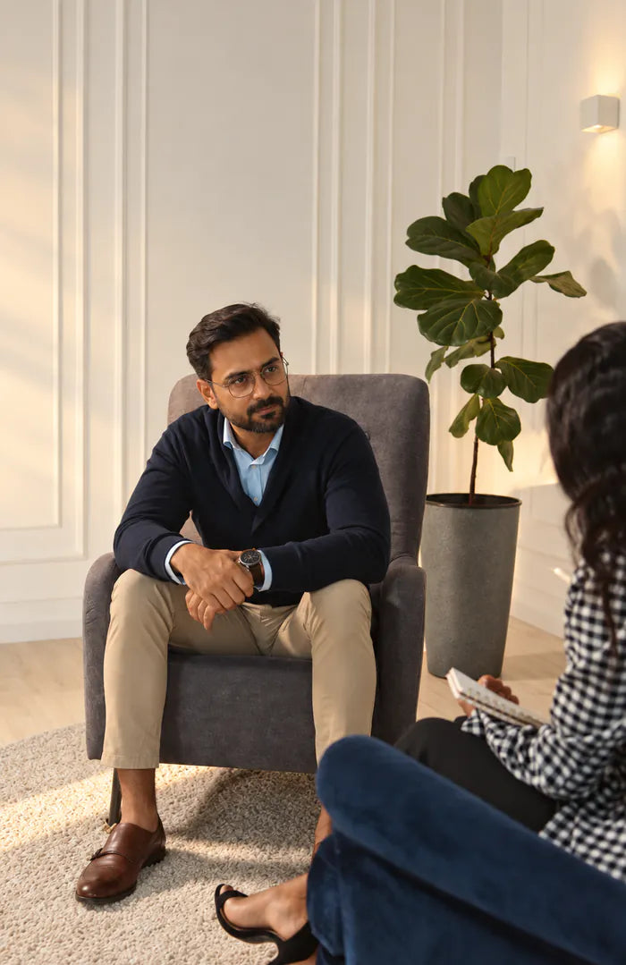 A psychologist seated in an armchair, listening during a session