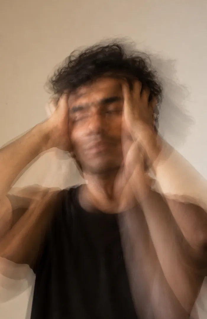 A man holding his head, blurred in motion