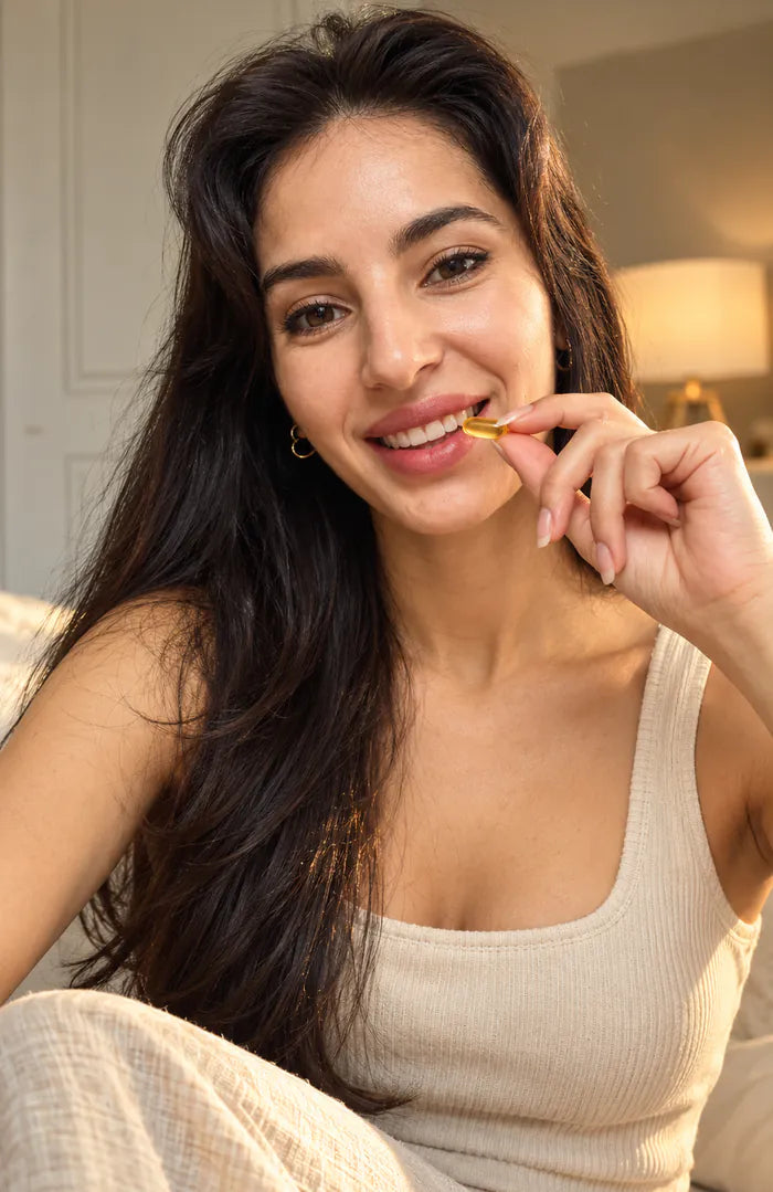 A smiling woman holding a supplement capsule
