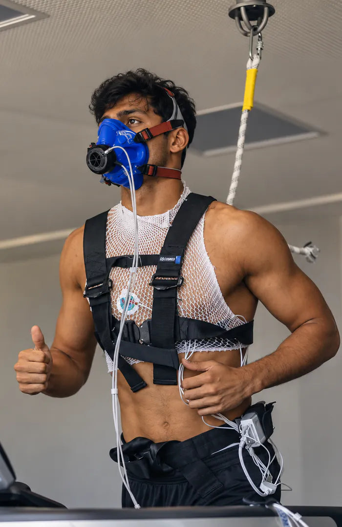A man on a treadmill wearing a breathing mask and monitoring harness for a VO2 max test