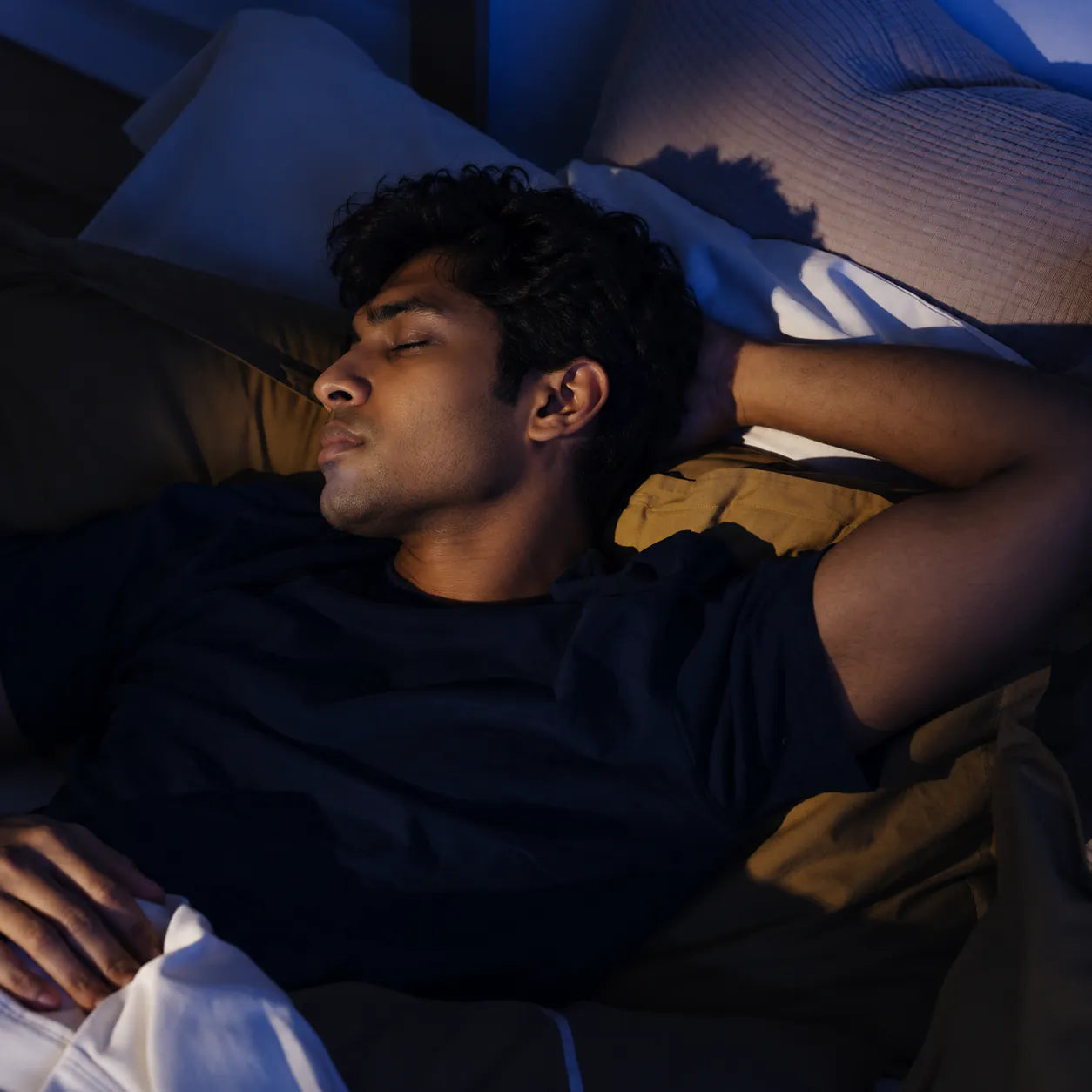 A man asleep on his side in a dim room